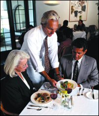 A waiter serving a couple their meal